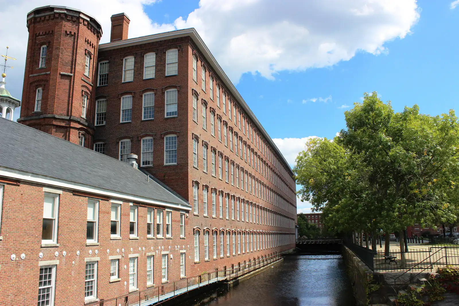 The brick Boott Cotton Mills and canal under a bright summer sky in Lowell, Massachusetts